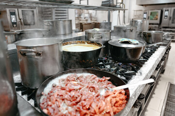 Food preparing in metal pots on the stove at professional kitchen