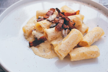 Rigatoni alla carbonara, italian pasta dish with eggs, hard cheese, cured pork, and black pepper.