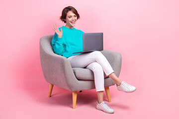 Fototapeta na wymiar Full length photo of gorgeous cheerful lady sitting chair chatting friends waving hand say hello isolated on pink color background