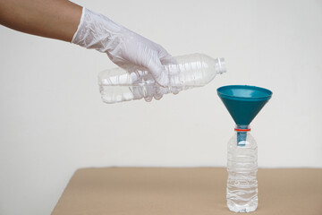 Closeup hand wear  glove holds bottle of water to pour water into bottle to do science experiment....