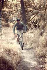 Developing speed during ride. Young man riding on bmx bike in forest, doing tricks, training....