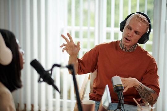 Emotional man in headphones talking to host when they are recording poscast