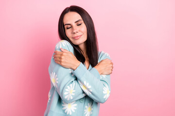 Photo of dreamy sweet woman dressed blue cardigan hugging herself closed eyes empty space isolated pink color background