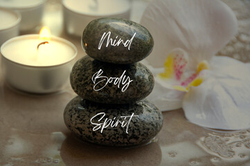 Mind, Body and Spirit words on zen stones with candle background. Health life concept