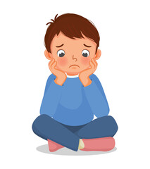 Sad little boy sitting on the floor with his chin resting on his hands