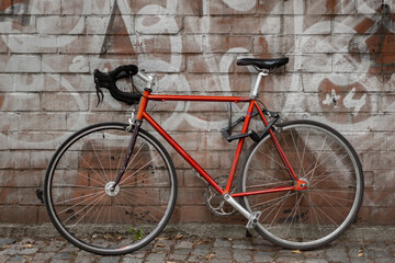 red road bike parked against wall with graffiti