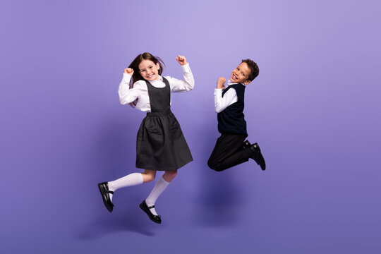 Photo of positive schoolkids girl boy jumping enjoy school sales raise fists up isolated bright color background