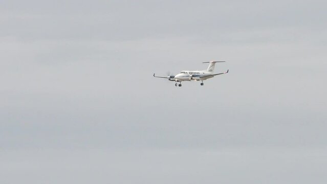 Generic Unmarked Twin-Turbo Propeller Private Plane Flying in a Cloudy Sky with Landing Gear Extended