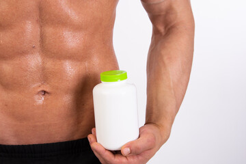 Sports, healthy eating and a healthy lifestyle. Young attractive man on a diet. Athletic handsome guy posing with sports nutrition in the studio.