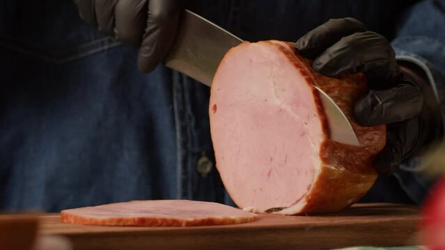Woman slices ham bacon meat thick pieces on a wooden board, beef or pork jamon. Chef cooking breakfast, smoked bacon in cafe. 
