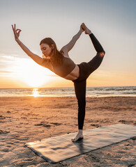 Fototapeta na wymiar Concentration and mental health. Yoga workout at sunset, the trainer is a slender woman with a beautiful body, the asana exercise uses a mat on the sand. Zen and meditation.
