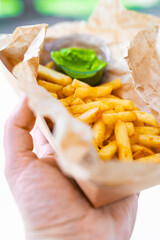 hands hold French fries and sauce. street food