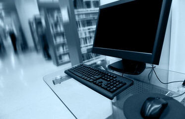 Computer in library with many books and shelves in the background