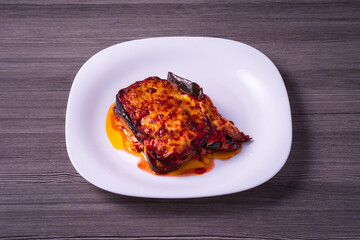 plate with eggplant parmesan on gray wooden table