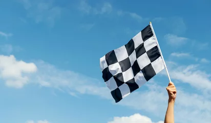 Fotobehang Formule 1 Checkered race flag in hand against blue sky  © xy
