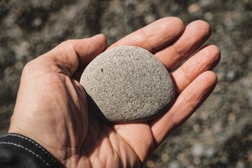 Man holding a smooth pebble in his hand in sunlight