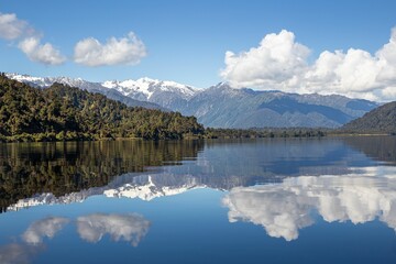 Landscape of the tranquil Lake Mapourika reflecting the majestic mountains in New Zealand © Sam Lawrence/Wirestock Creators
