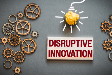 Disruptive innovation text on wooden block. Between gears, precision mechanisms and drawn light bulb, business concept