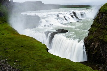 the waterfall is flowing very fast on a cloudy day in iceland