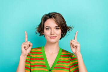 Photo of good mood pretty lady wear striped cardigan pointing two fingers up empty space isolated...