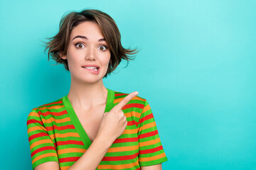 Photo of pretty doubtful lady wear striped cardigan biting lip showing finger empty space isolated...