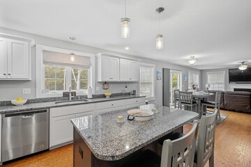 Kitchen with white cabinets, a gray granite countertop, and modern appliances.