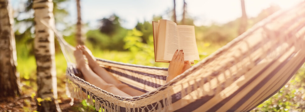 Woman lying in the hammock and reading an interesting book.