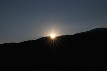 Scenic view of sun setting behind a mountain range