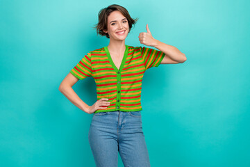Fototapeta na wymiar Photo of pretty shiny lady wear striped cardigan smiling showing thumb up isolated teal color background