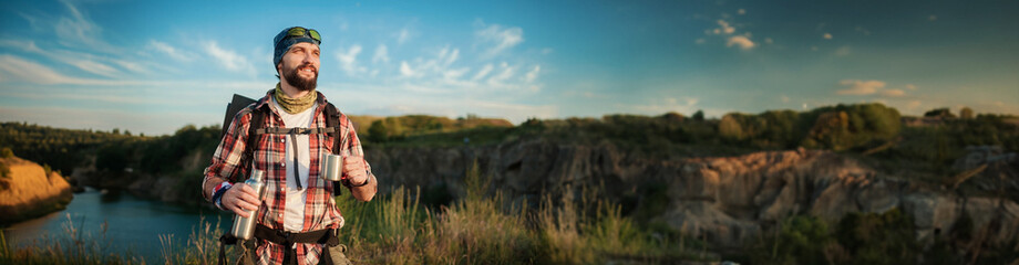 Young man going hiking on hills. Man standing on peak of beautiful mountain and enjoying...