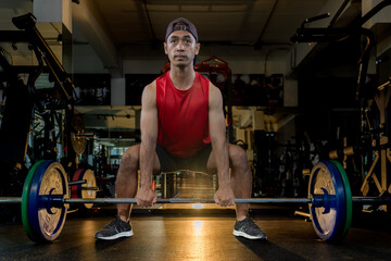 handsome muscular asian young man weight lifting with olympic barbell strong exercise at modern...