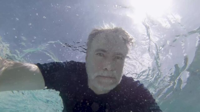 Mature man swimming underwater