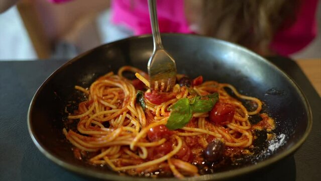 Woman eating italian spaghetti with tomatoe and basilic in a restaurant