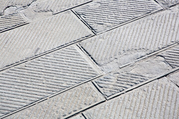 Old and damaged italian paving made with chiseled grey sandstone blocks in a pedestrian zone - The...