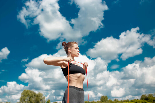 athletic woman goes in for sports in nature in summer on the beach with resistance band