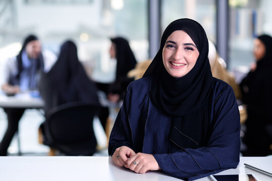 Middle Eastern Arab at office with Emirati Arabic workmates at the background. Emir national wearing Abaya at meeting room