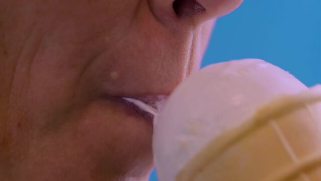 a woman eats ice cream on a blue background close-up