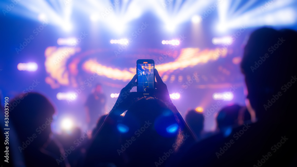 Wall mural People holding smart phone and recording and photographing in concert , silhouette of hands with mobile , event background concept