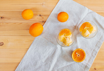 Orange ice cream in glass bowls and fresh oranges near. Top view, copy space.