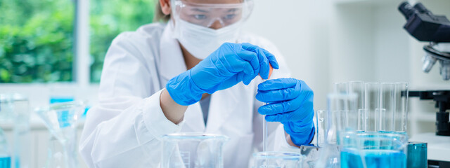 Close up of scientist is dropping blue liquid substance in science test tube in laboratory. Concept of science, biochemistry, chemical, diagnosis, biotechnology. Substance study analyzing experiment