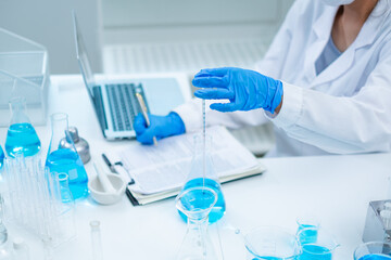 Fototapeta premium A female scientist is checking a temperature of substance in laboratory. Concept of checking the quality of sample liquid or biotechnology and medicine research, examining, inspection or discovery.