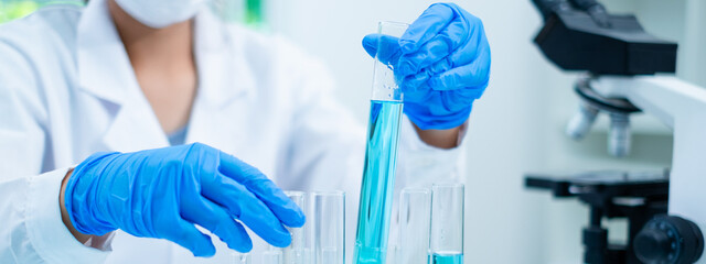 Close up of scientist's hand is holding a blue chemical substance in laboratory. Concept of...