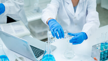 Fototapeta premium Close up of Female scientist or researcher is pouring substance or liquid in to a sample test tube. Concept of science, biochemistry, chemical, biotechnology laboratory. Analyzing and experiment