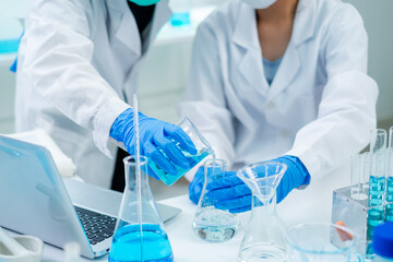 Fototapeta premium Close up of Female scientist or researcher is pouring substance or liquid in to a sample test tube. Concept of science, biochemistry, chemical, biotechnology laboratory. Analyzing and experiment