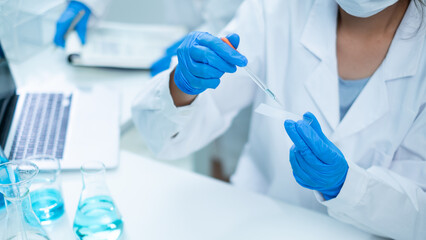 Close up of scientist is dropping blue liquid substance in science test tube in laboratory. Concept of science, biochemistry, chemical, diagnosis, biotechnology. Substance study analyzing experiment