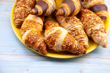 Chocolate croissants or croissant with nut crumbs on a plate. Delicious breakfast on the table. Tasty sweet baking dessert for coffee. Food background. Fresh buttery croissants rolls