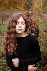 a girl in an autumn forest with an owl