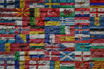 all colorful painted national european flags on a massive big old brick wall.