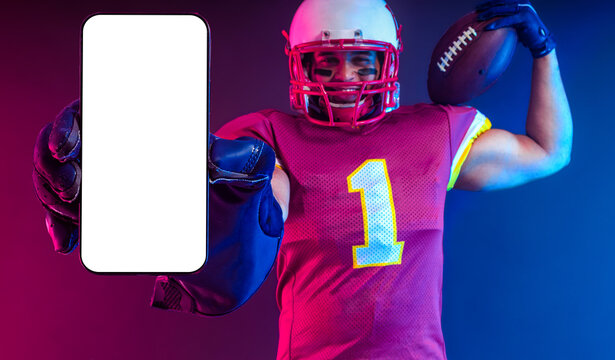 Sports Betting. American Football Player. Sports betting on futebol. Bets in the mobile phone application. Advertisement app. Man Showing At White Empty Smartphone Screen. Cellphone Display Mock Up