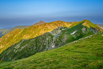 Obraz premium The Fagaras Mountains at sunrise. A view on the Mount Paltinul from the Iezerul Caprei, Carpathians, Romania.
